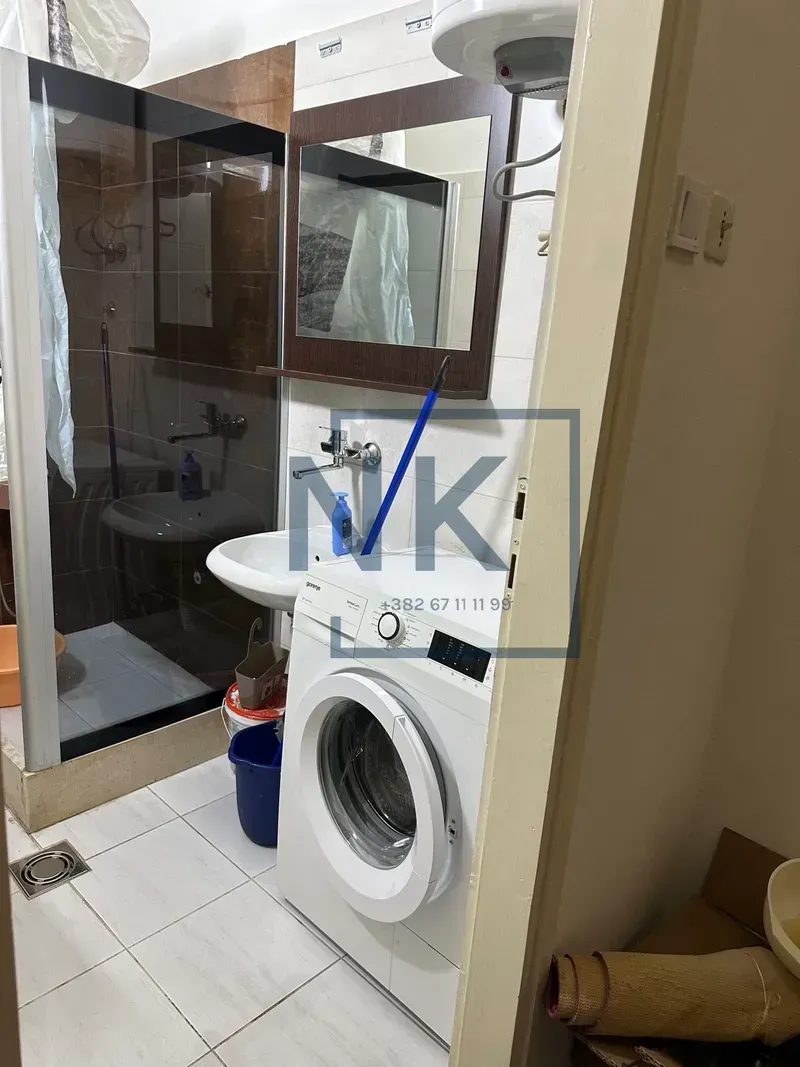 Manje kupatilo sa tuš kabinom, umivaonikom i veš mašinom.