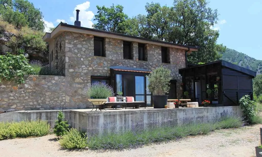 Kamena kuća sa prostranom terasom i uređenim dvorištem.