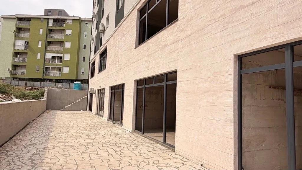 Exterior of a commercial space with a paved courtyard and large glass display windows.