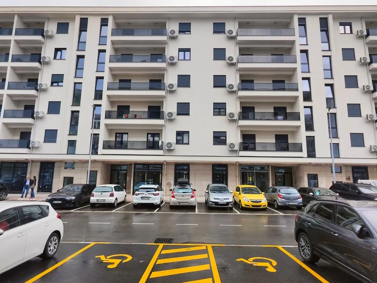 Facade of a modern residential building with parking in front of the entrance.