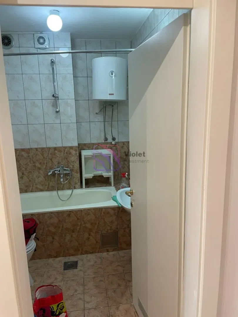 View of the bathroom with a bathtub and a water heater through an open door.