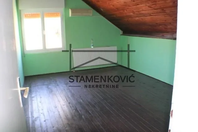 Empty attic room with wooden flooring and green walls.