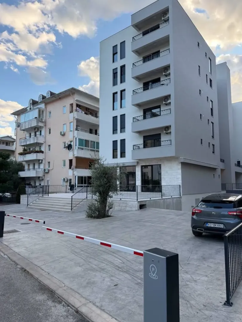 Exterior of a modern multi-family apartment building with parking and a security barrier.