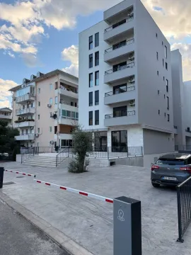 Exterior of a modern multi-family apartment building with parking and a security barrier. - image 2