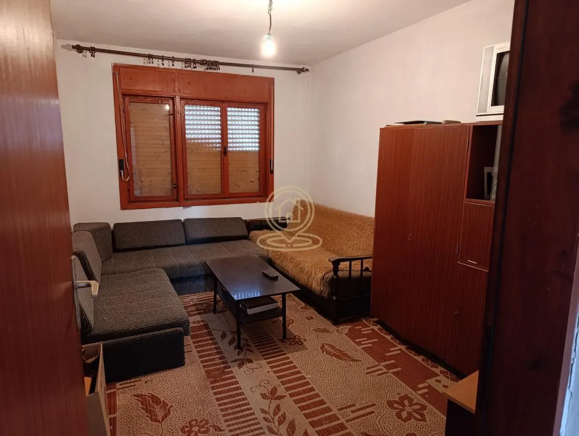 Dnevna soba sa garniturom za sedenje, stočićem i drvenim ormarom.