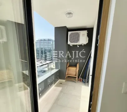 Manji zatvoreni balkon sa staklenom ogradom i pogledom na grad. - image 9