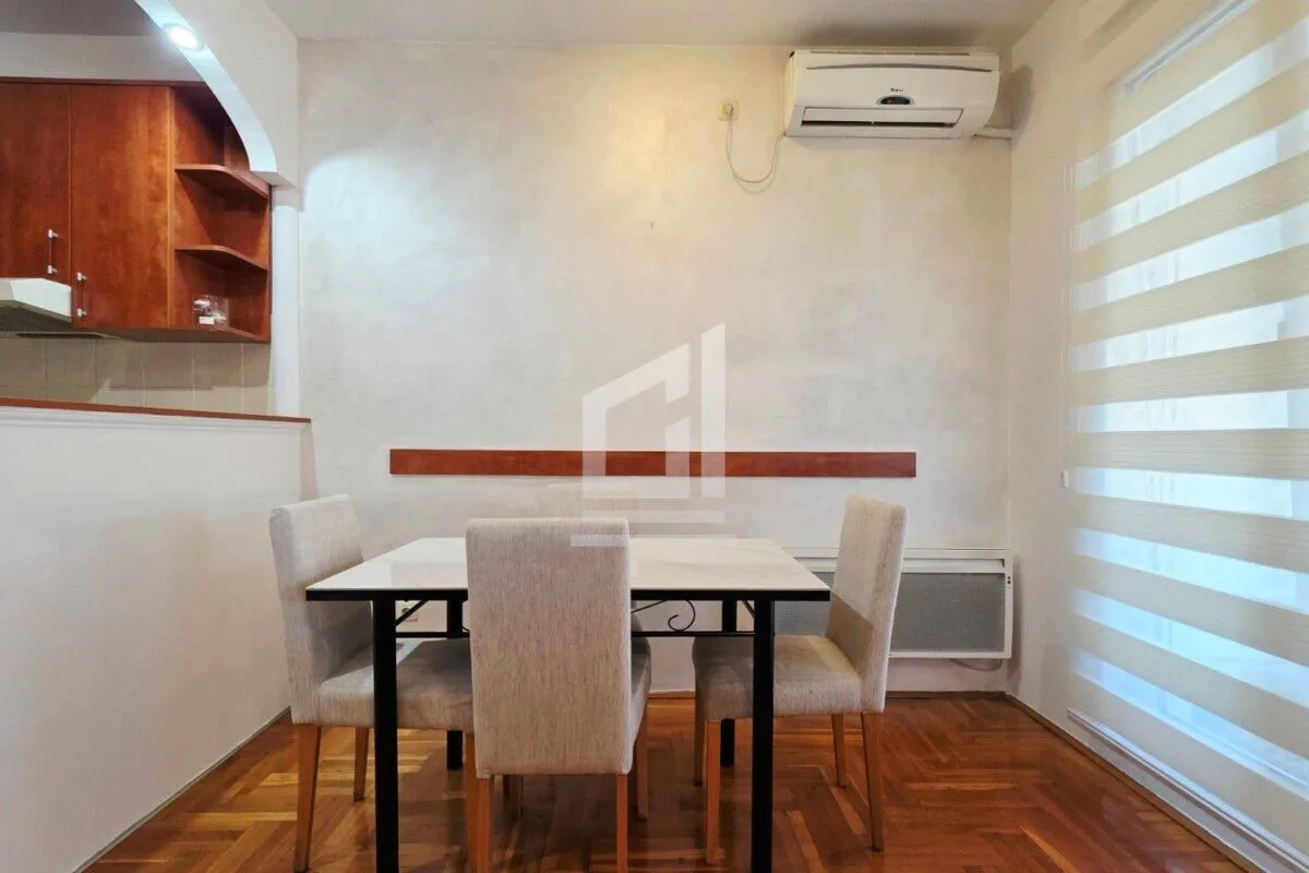 Dining area with a table and four chairs, with part of the kitchen in the background.