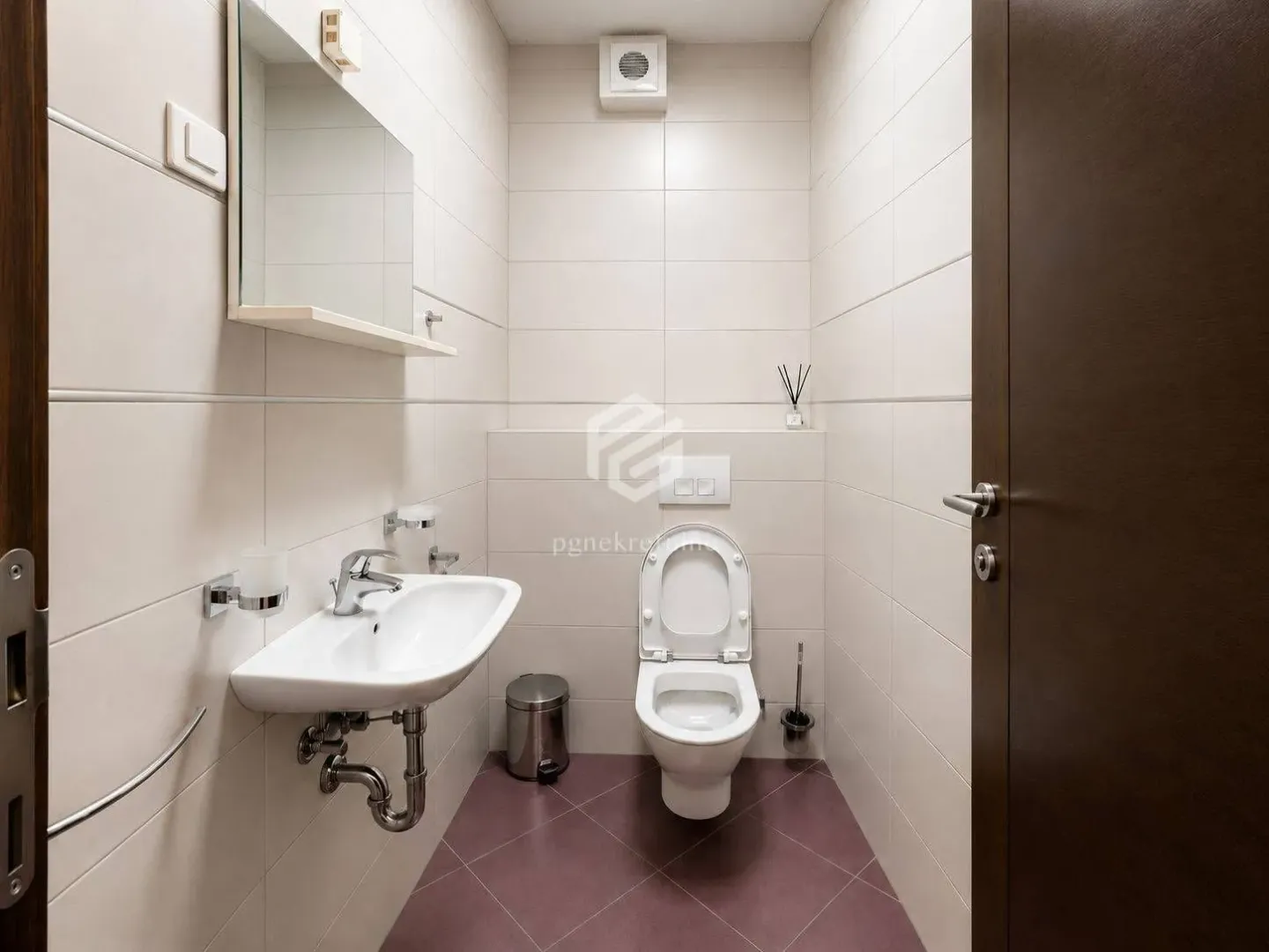 Small bathroom with a sink and toilet tiled in light tiles.