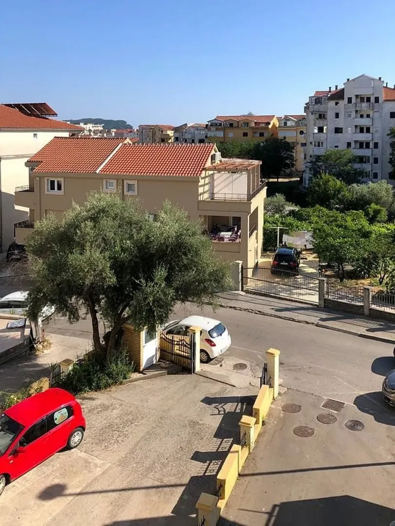 View from the window showing surrounding buildings, street, and yard.