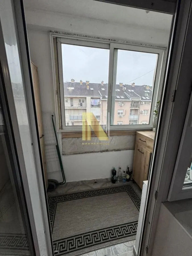 Zastakljeni balkon sa pogledom na okolne zgrade.