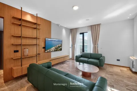 Dnevna soba sa drvenim zidnim panelom, zelenim garniturama i pogledom na more. - image 9
