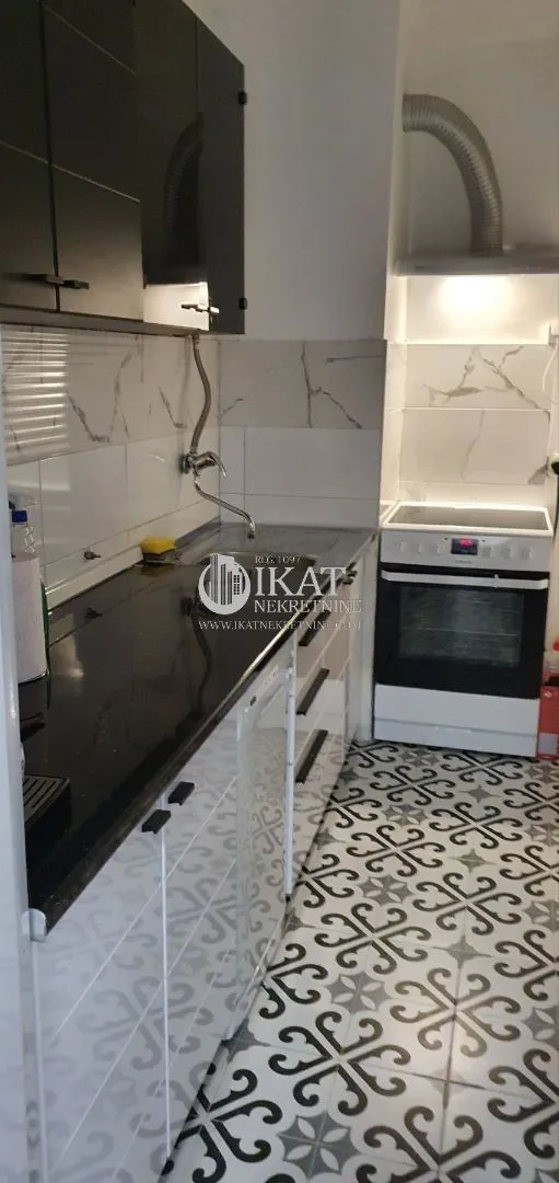 Small kitchen with black and white cabinets and a stove.