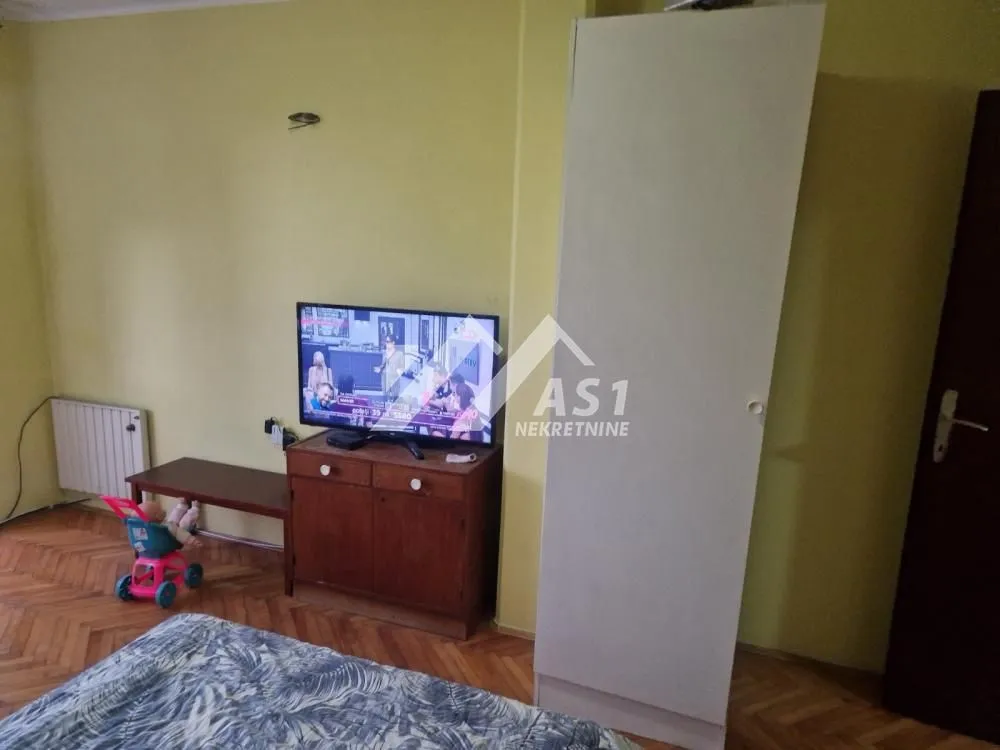 Manja spavaća soba sa krevetom, garderoberom i televizorom.