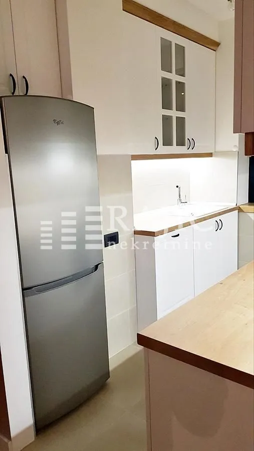 Modern kitchen with white cabinetry and a large refrigerator.