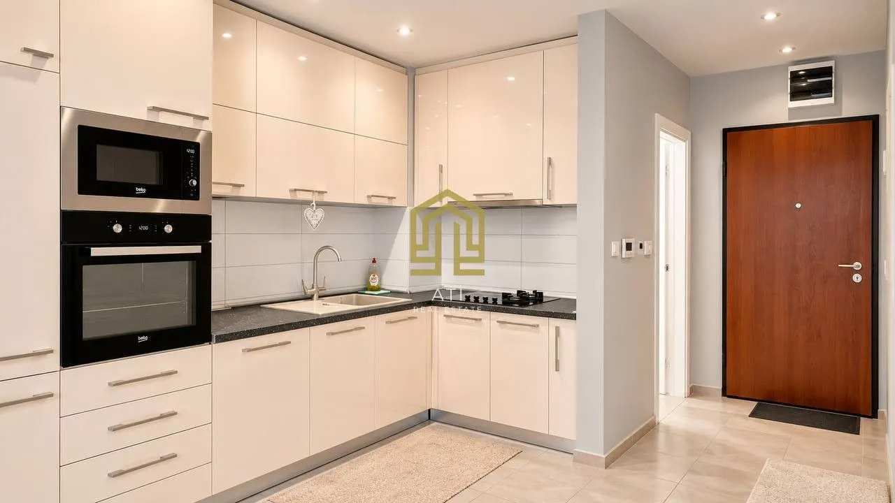 Modern fitted kitchen in light tones next to the entrance.