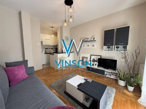 Dnevna soba sa garniturom, televizorom i pogledom na kuhinju u pozadini. - image 8