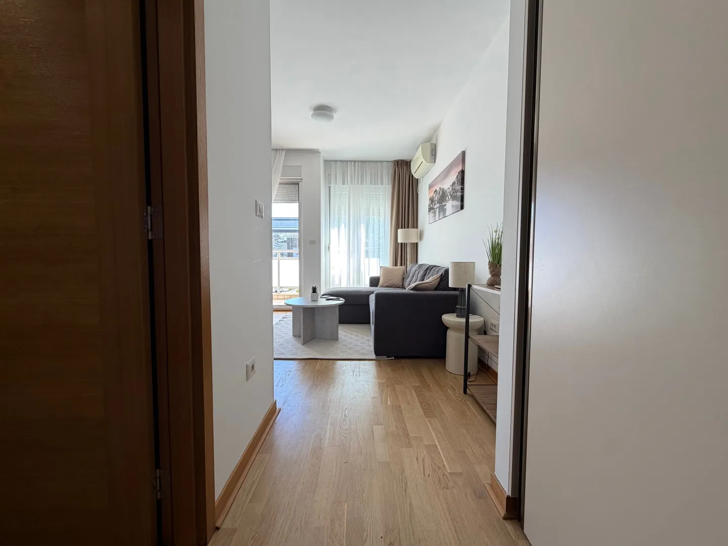 View from the hallway into a bright living room with a sectional sofa.