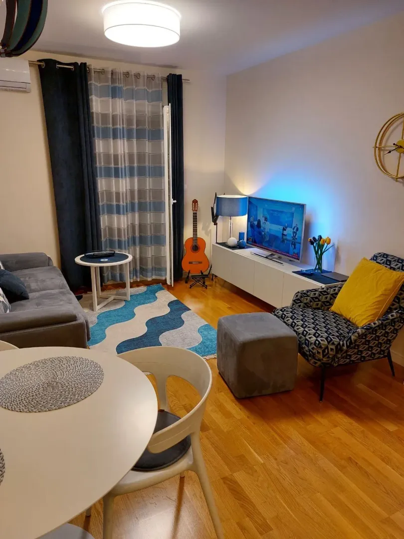 Living room with sofa, TV, and dining table.
