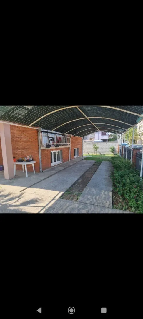 A yard with a covered parking space in front of the house.