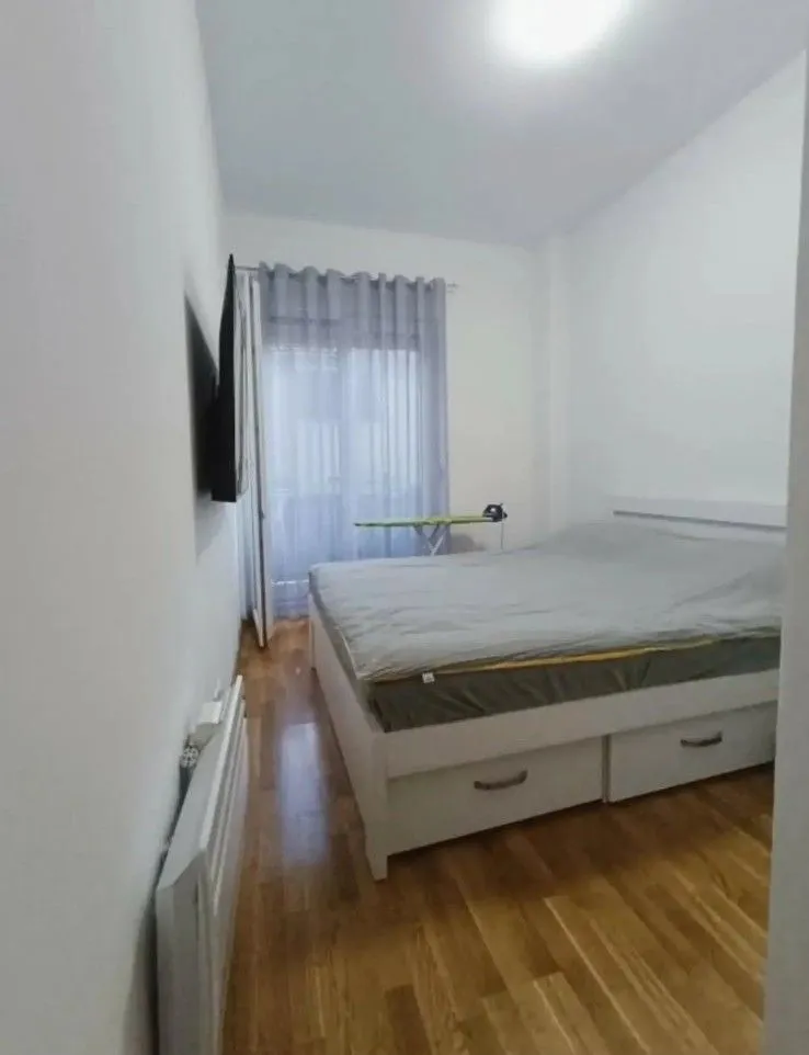 Bright bedroom with a double bed, wooden flooring, and access to the terrace.