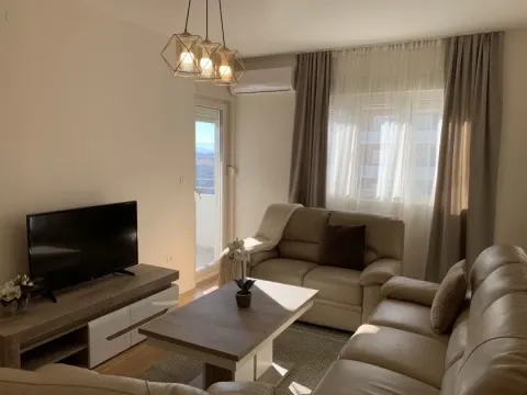 Furnished living room with sofa, TV, and balcony access. - image 2