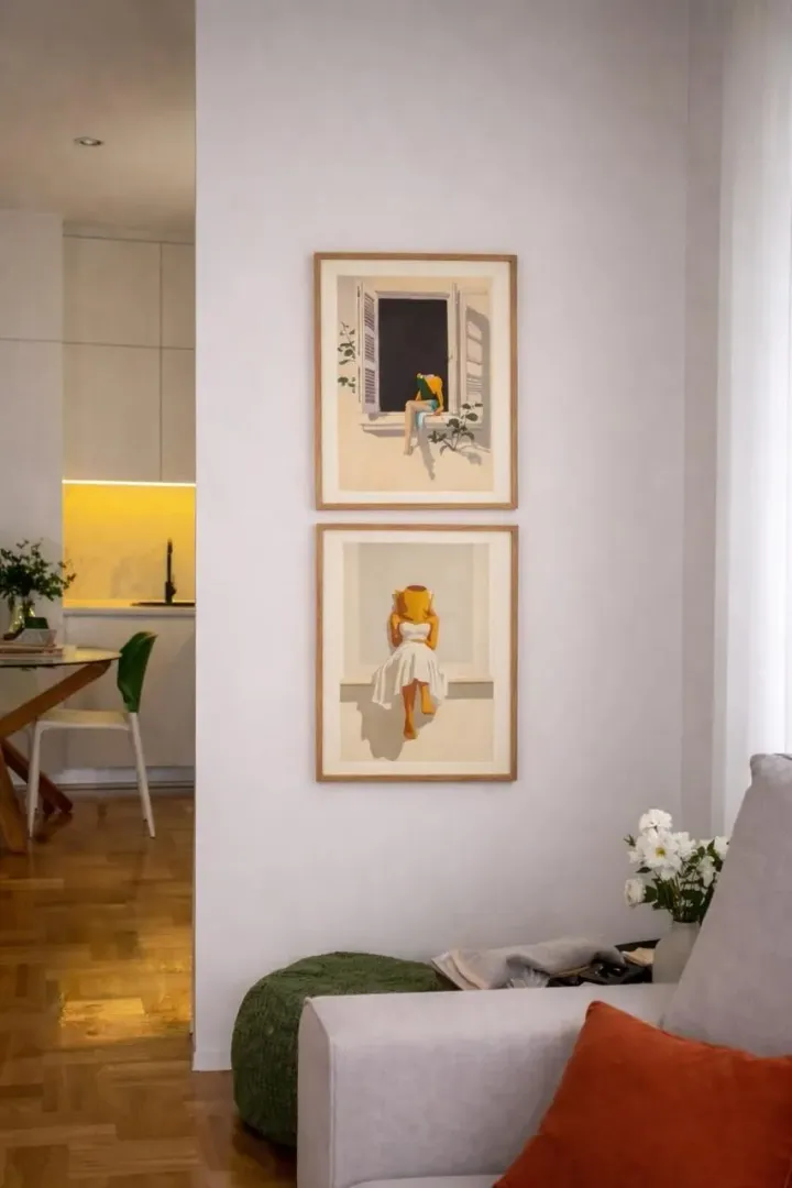 Living room with sofa and art paintings on the wall, overlooking the dining area and kitchen.