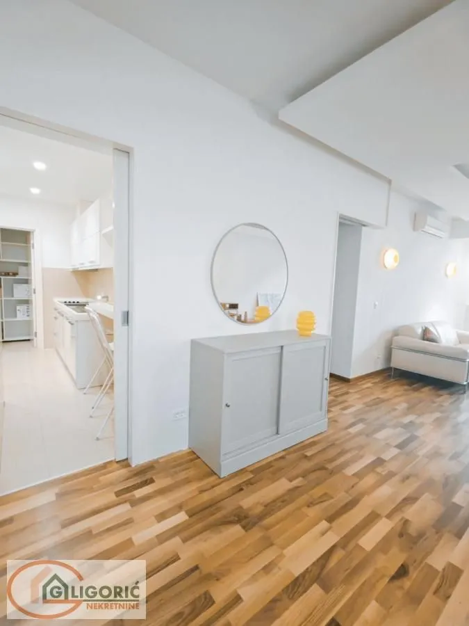 Living room with wooden flooring, a sideboard, and a view into the kitchen.