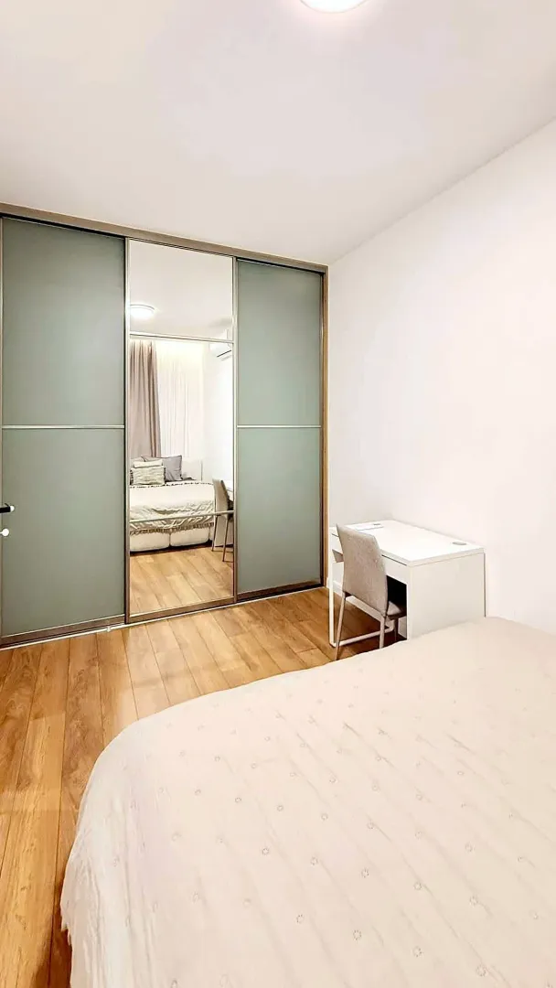 Bedroom with a large built-in mirrored wardrobe and a desk.