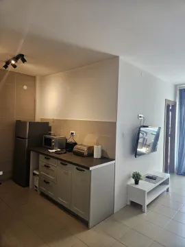 Compact kitchen with a refrigerator, appliances, and countertops, connected to the living area. - image 2