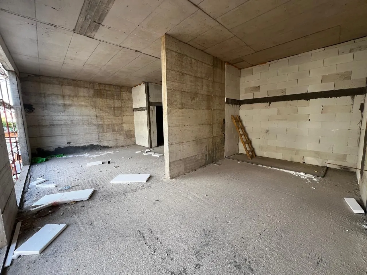 View of an unfinished space under construction with concrete pillars and block walls.