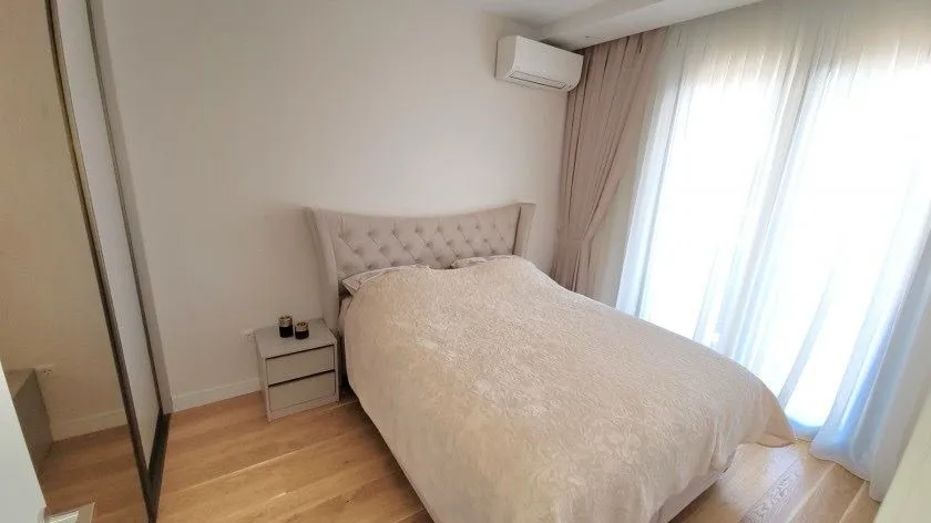 Uređena spavaća soba sa bračnim krevetom, garderoberom i klima uređajem.