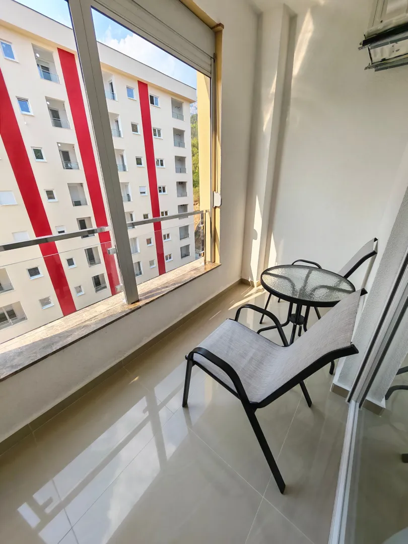 Manji zatvoreni balkon sa staklenim stolom i dvije stolice.