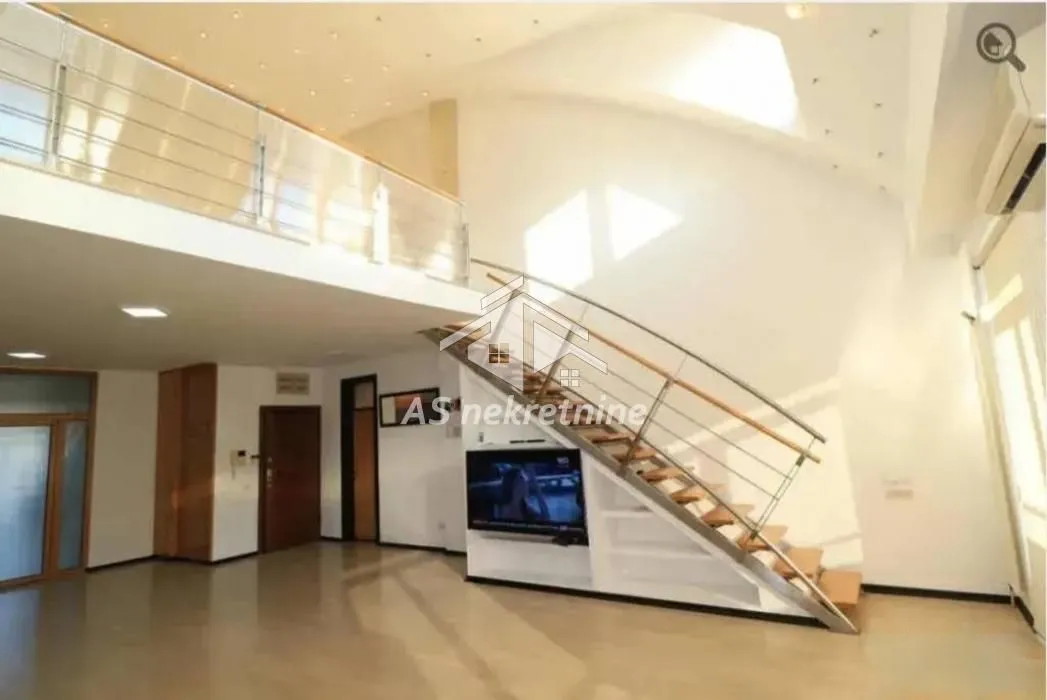 Spacious living room with a staircase and a gallery on the upper floor.