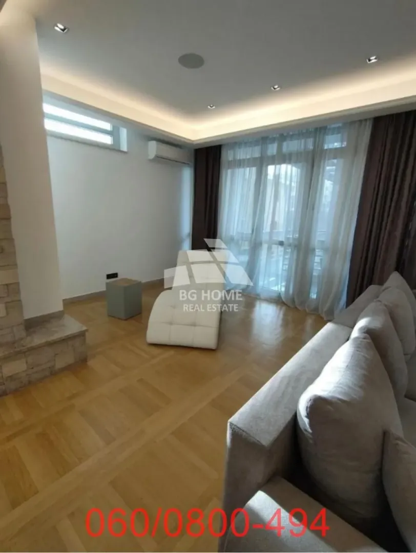 Living room with furniture and large windows letting in natural light.