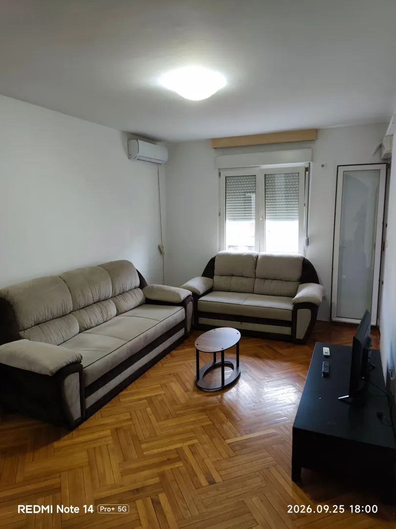Namještena dnevna soba sa garniturom i TV komodom.