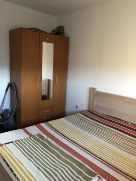 Simple furnished bedroom with a wooden wardrobe and a bed. - image 6