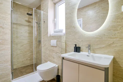 Moderne kupatilo sa tuš kabinom, umivaonikom i ugradnom šoljom obloženo keramičkim pločicama u boji mermera. - image 4