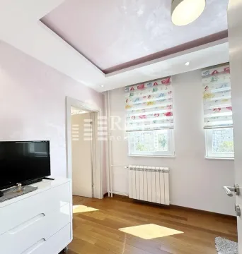 Bright bedroom with wooden flooring, a white chest of drawers, and a television. - image 3