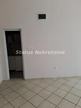 Empty room with ceramic tiles and a view of a small kitchen through the doorway. - image 4