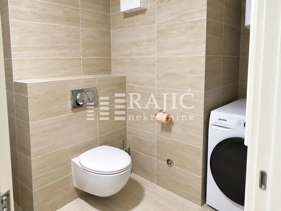 Modernly equipped bathroom with a wall-hung toilet and a washing machine.
