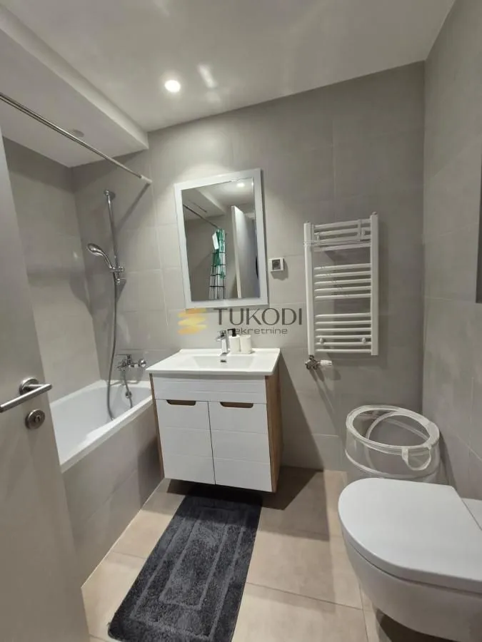 Modern equipped bathroom with a bathtub, washbasin, and toilet.