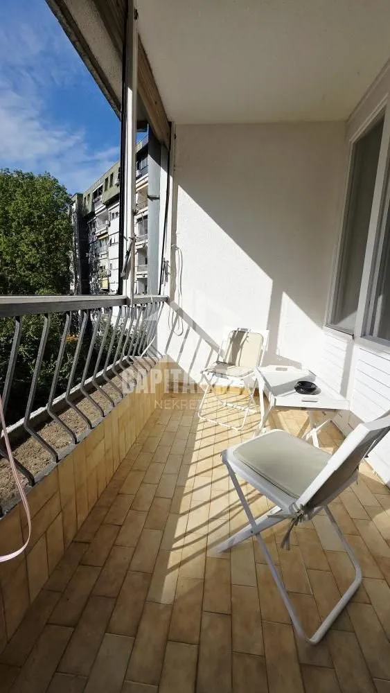 Covered balcony with chairs and a small table.