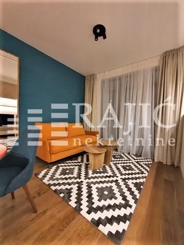 Living room with an orange sofa, patterned rug, and wooden flooring.