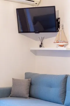 Part of the living room with a sofa, wall-mounted TV, and a shelf with decorations. - image 14