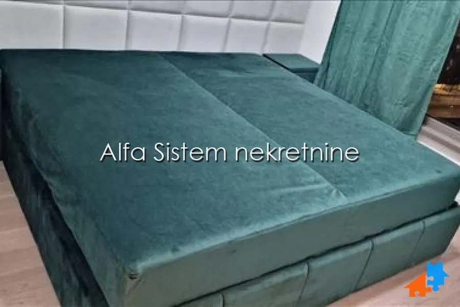 Prostrani bračni krevet sa zelenom tapaciranom konstrukcijom u spavaćoj sobi.