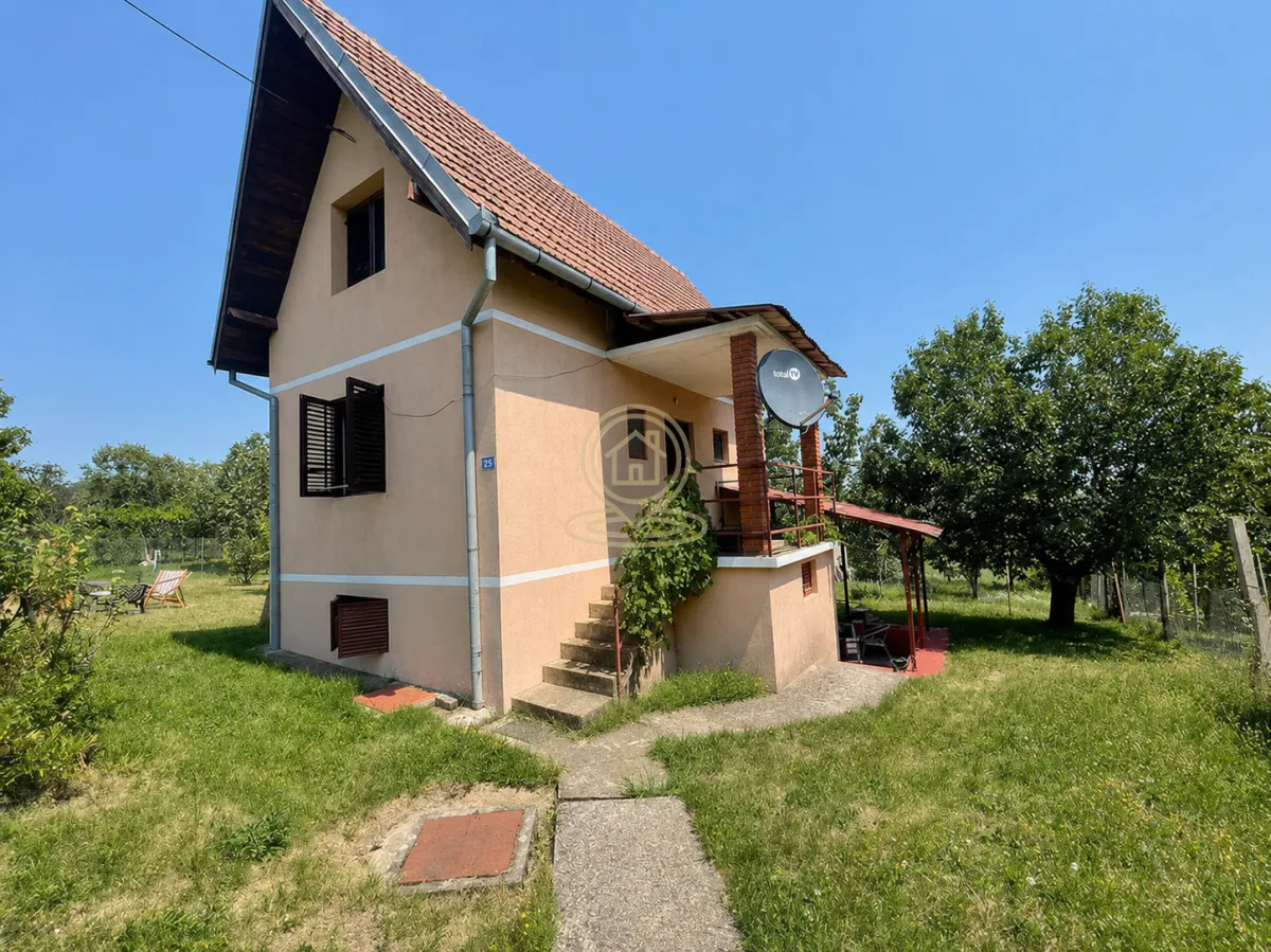 Pogled na spoljašnjost kuće sa dvorištem i zelenilom.