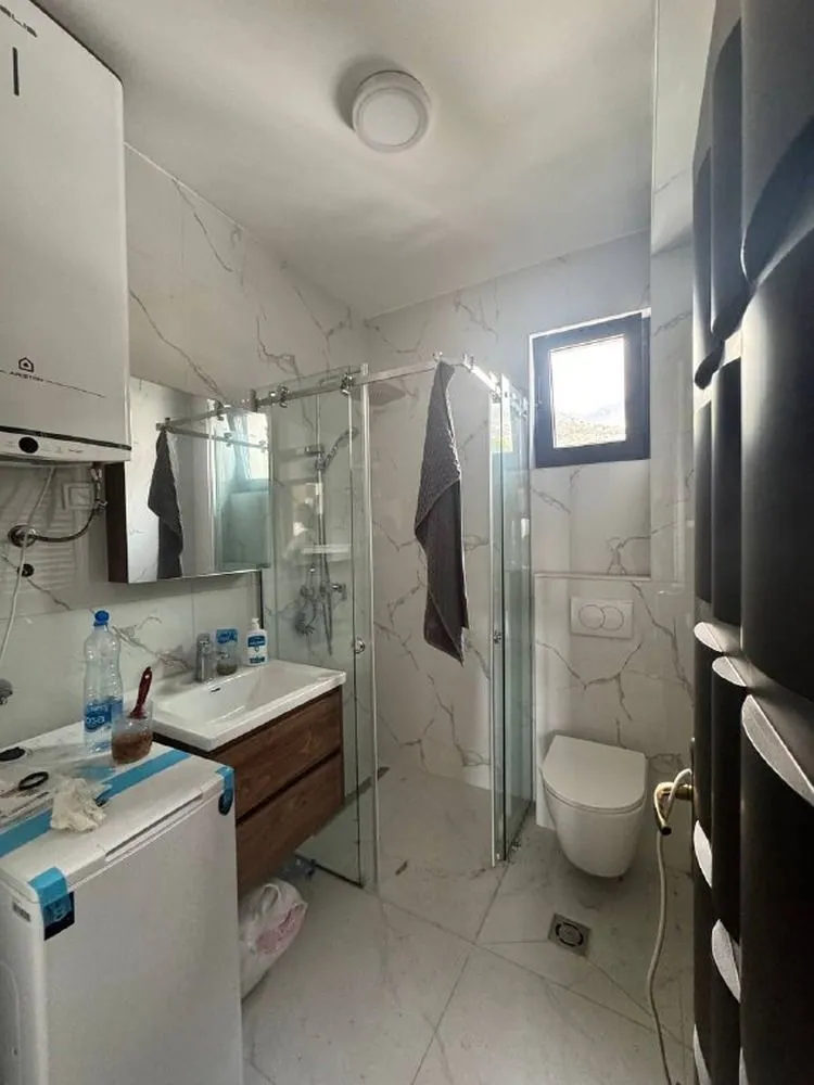 Manje kupatilo sa tuš kabinom, umivaonikom i WC šoljom.