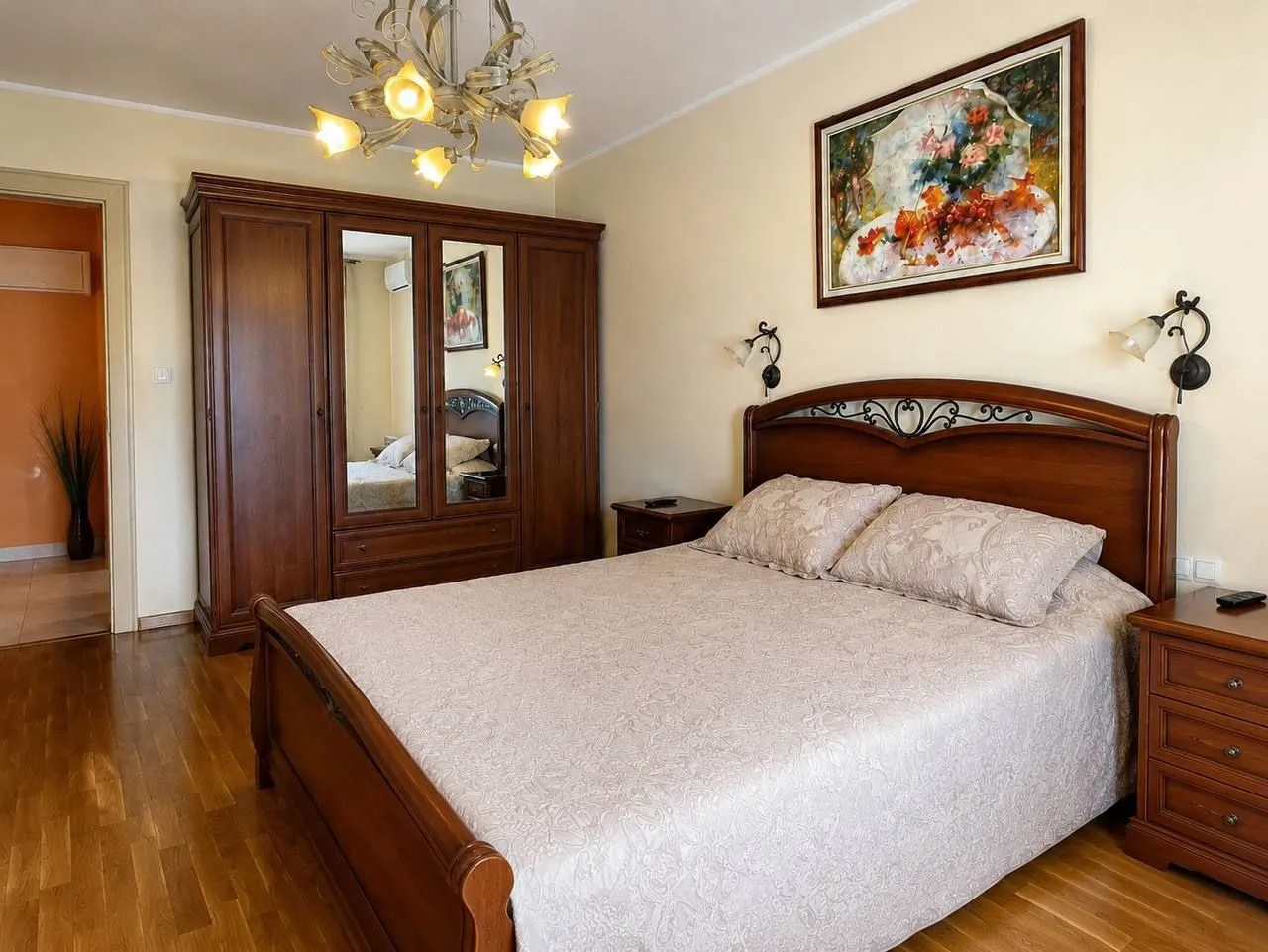 Furnished bedroom with a double bed, wooden wardrobe, and parquet flooring.