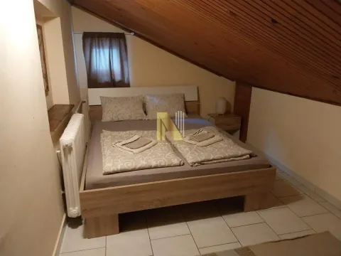 Spavaća soba sa bračnim krevetom i kosim plafonom obloženim drvetom. - image 8