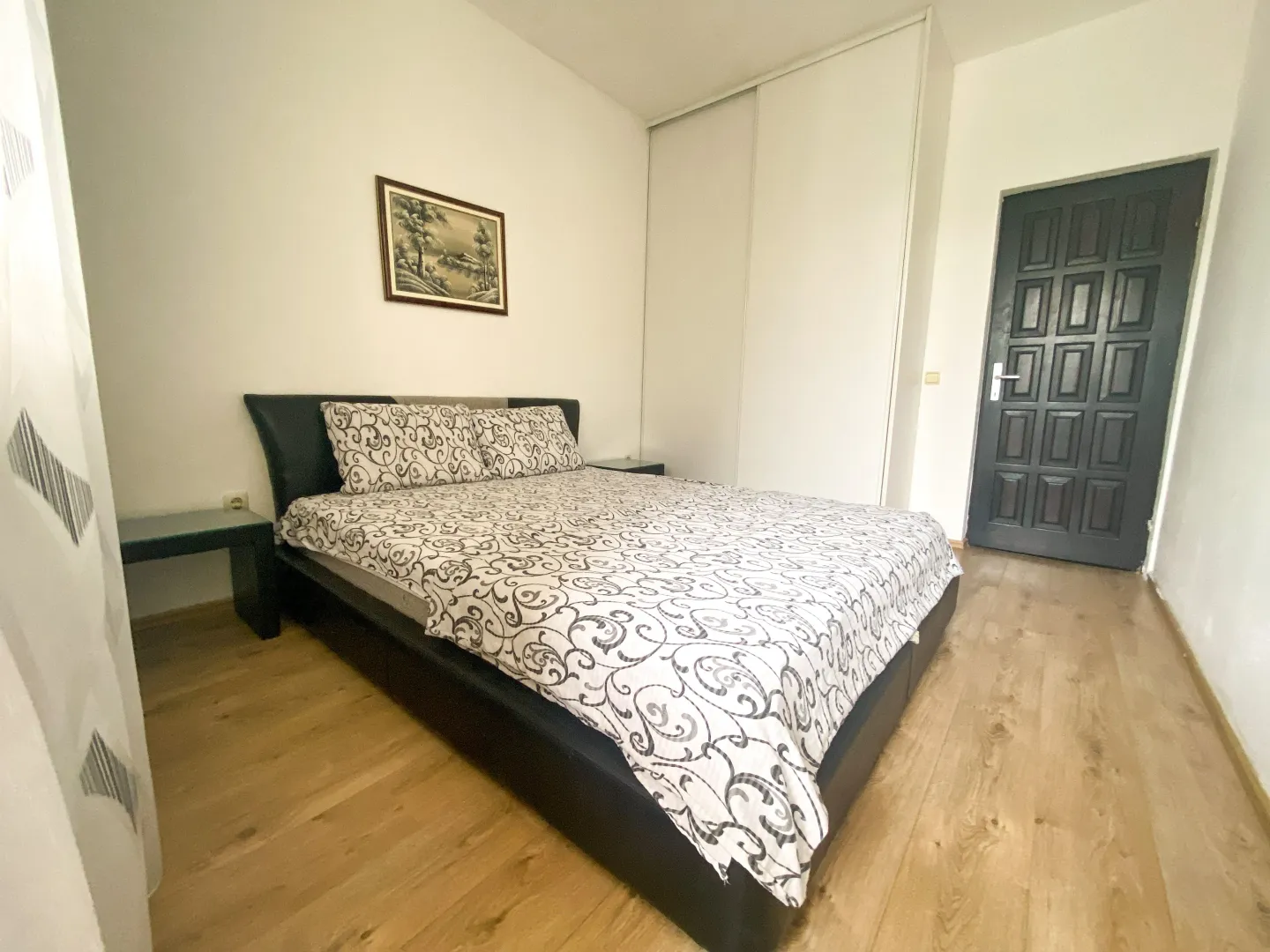 Furnished bedroom with a double bed, wardrobe, and a door.